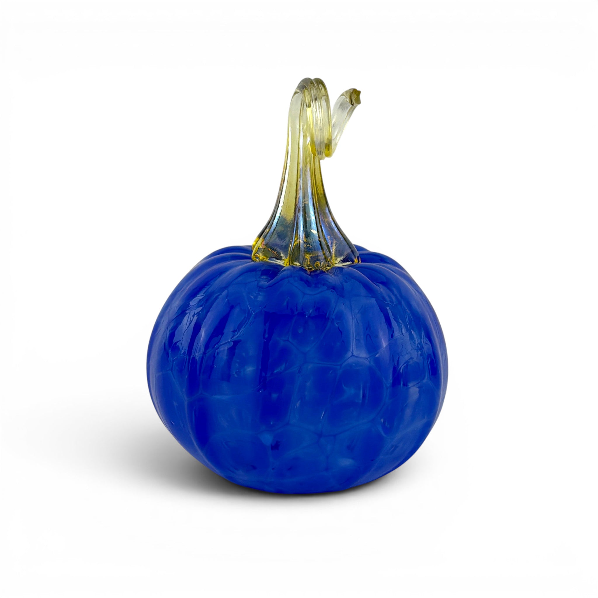 A decorative glass pumpkin figurine with a deep cobalt blue body and a translucent yellow-green stem, shown on a clean white background.