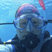 Lisa Oakley scuba diving underwater wearing a blue snorkel mask, black air regulator, pink and blue patterned headband, and a snorkel tube.