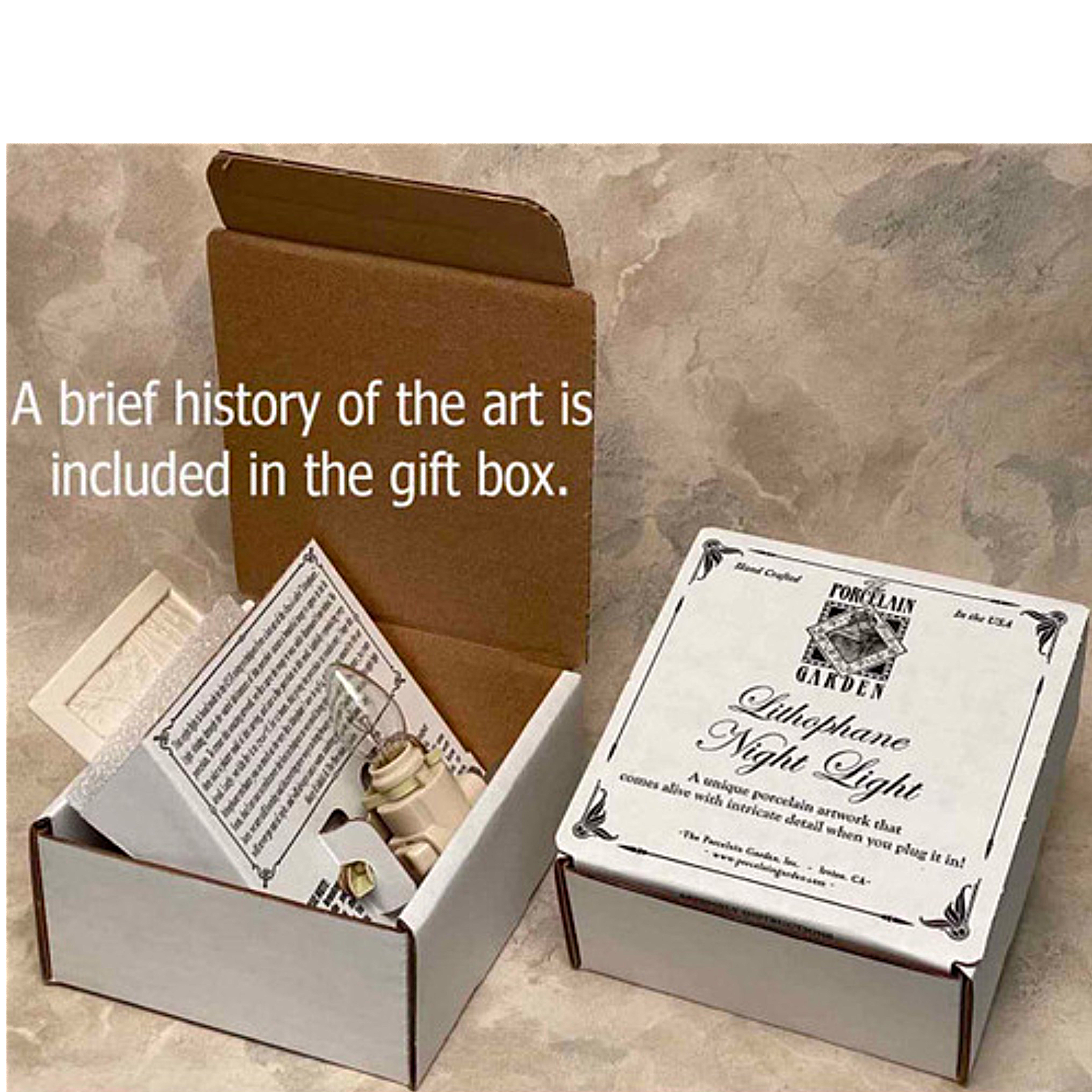 An open gift box and a closed square box for anight light. The open box contains a brief history of the art, which is included in the gift box.