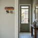 Wooden key holder on a wall with a door and hallway in the background