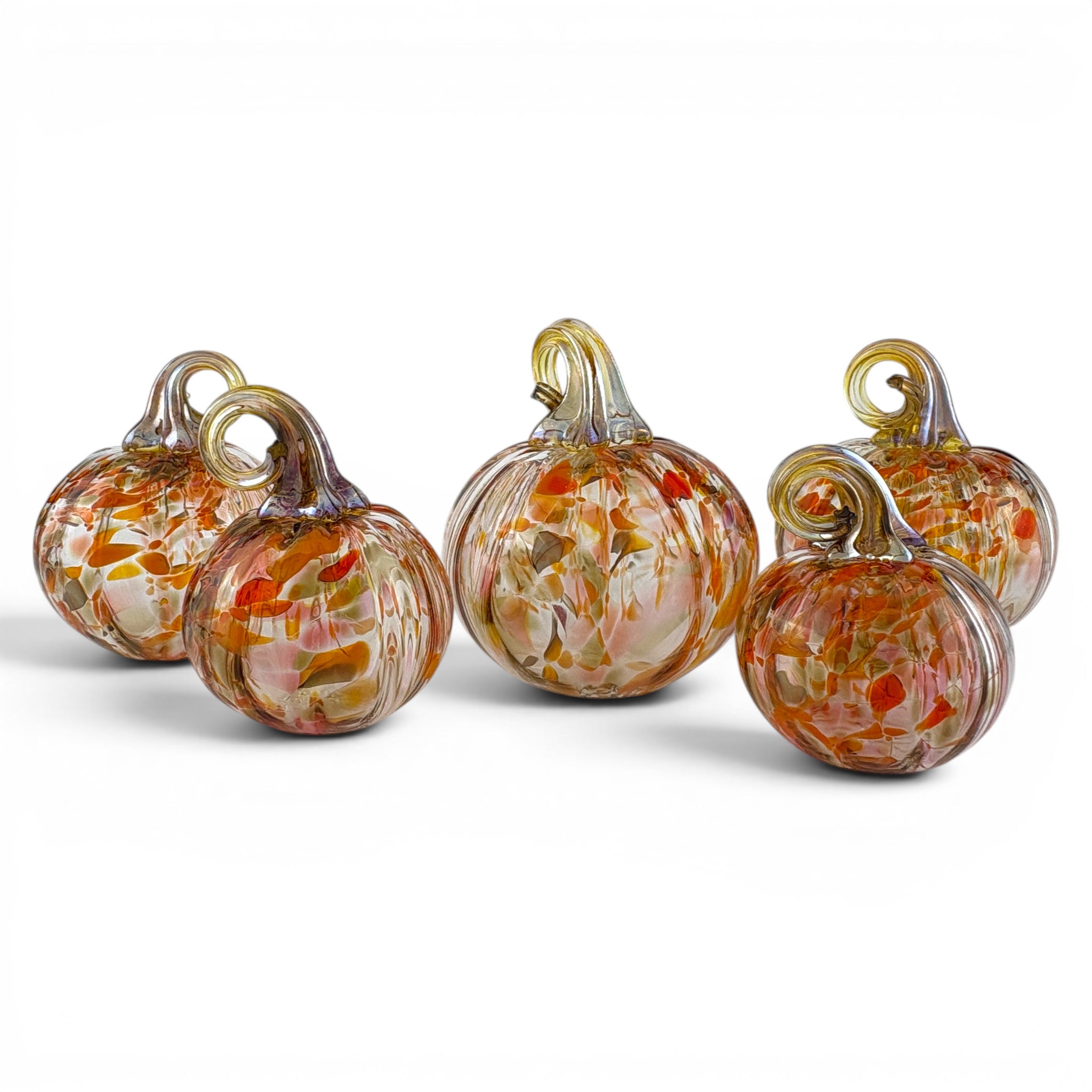 Five hand-blown glass pumpkins with textured orange, red, and white swirls and gold-toned stems, arranged on a white background.