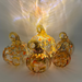 Five decorative glass pumpkins with ribbed textures and looped handles, filled with orange, yellow, and white marbled swirls, arranged on a reflective surface with dramatic light projections behind them.