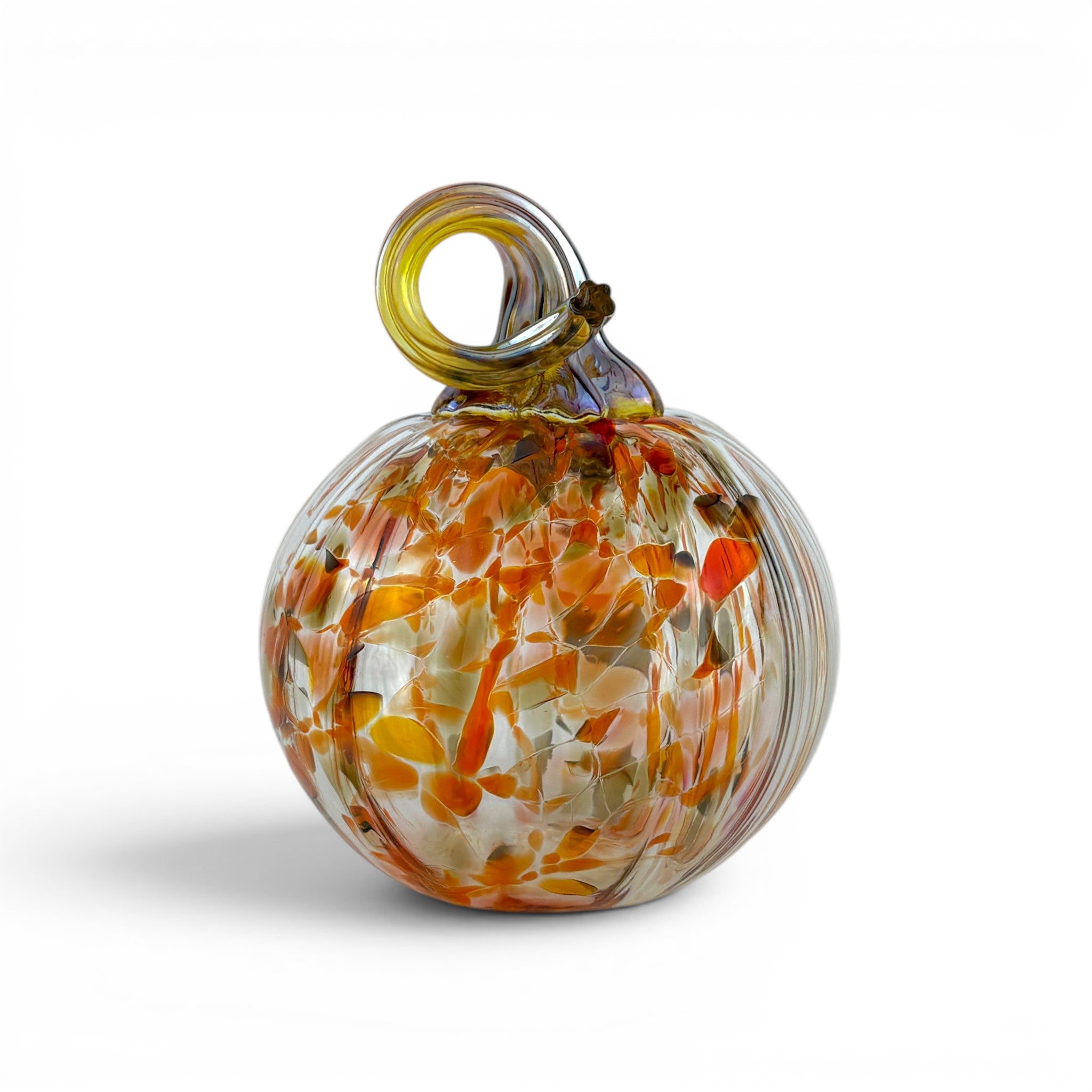 A hand-blown glass ornament with a rounded body containing orange, yellow, and white leaf-like swirls, topped with a small loop handle, shown on a white background.