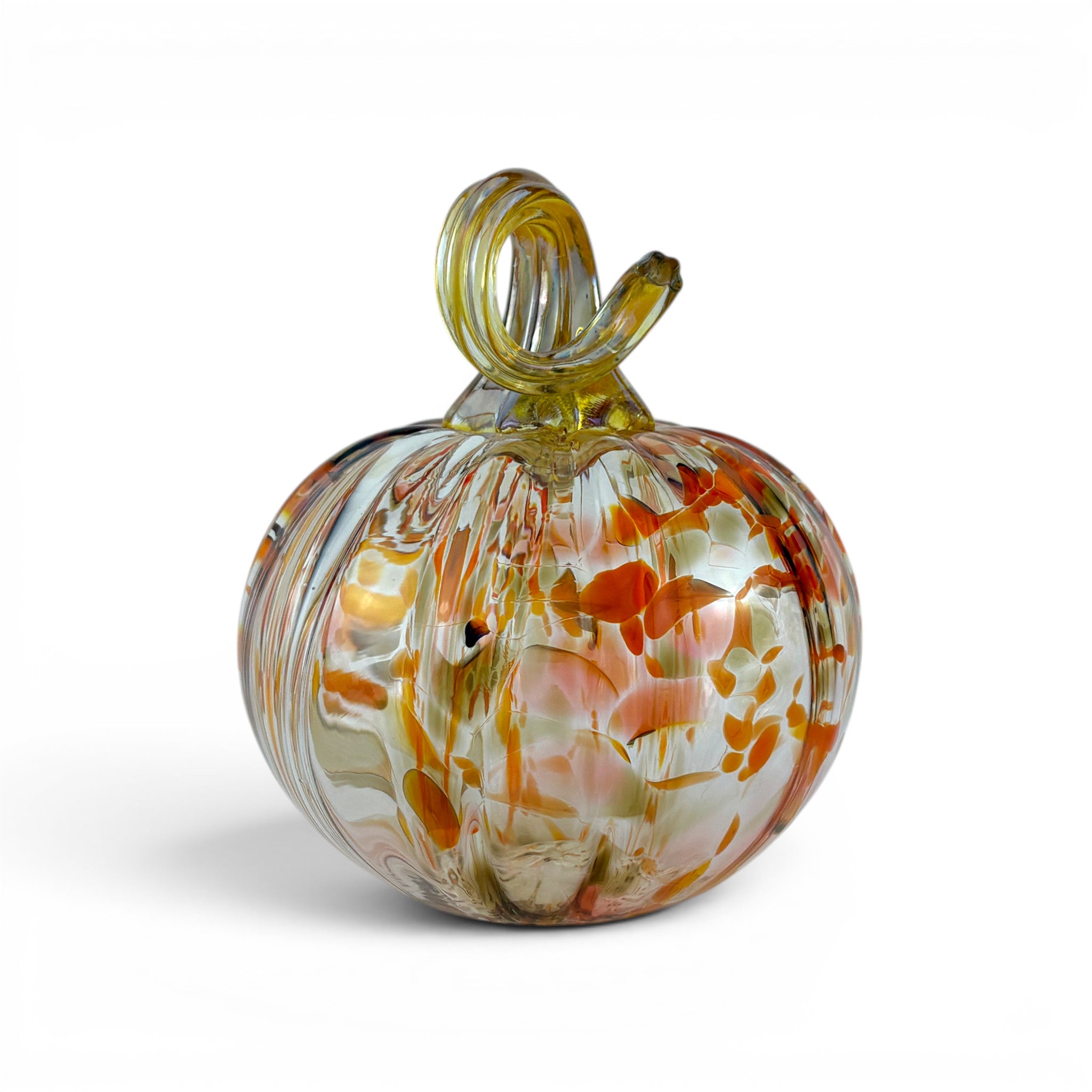 A decorative hand-blown glass pumpkin with a twisted stem, featuring marbled swirls of orange, yellow, and white on a clear glass base, set against a plain white background.