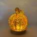 A decorative glass pumpkin displayed on an LED light base featuring a textured pattern of yellow, orange, and green glass. 