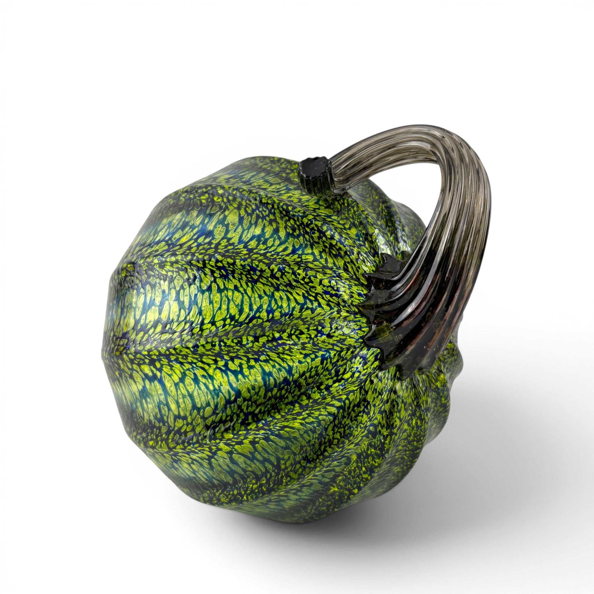 A decorative glass pumpkin with a textured green and yellow marbled pattern and a dark smoky stem. 