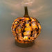 A handcrafted glass pumpkin with an illuminated marbled pattern in amber, gold, orange, and dark brown tones, sitting on an LED display light with a round wooden base. 