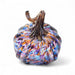 Multicolored handblown glass pumpkin with a golden brown stem on a white background