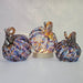 Three multicolored glass pumpkins on a light gray background