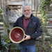 Paul Ray holding a ceramic bowl outdoors with a wooden fence in the background
