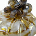 close view of a handcrafted glass pumpkin with white, gold, and a curled, ribbed golden browm stem.