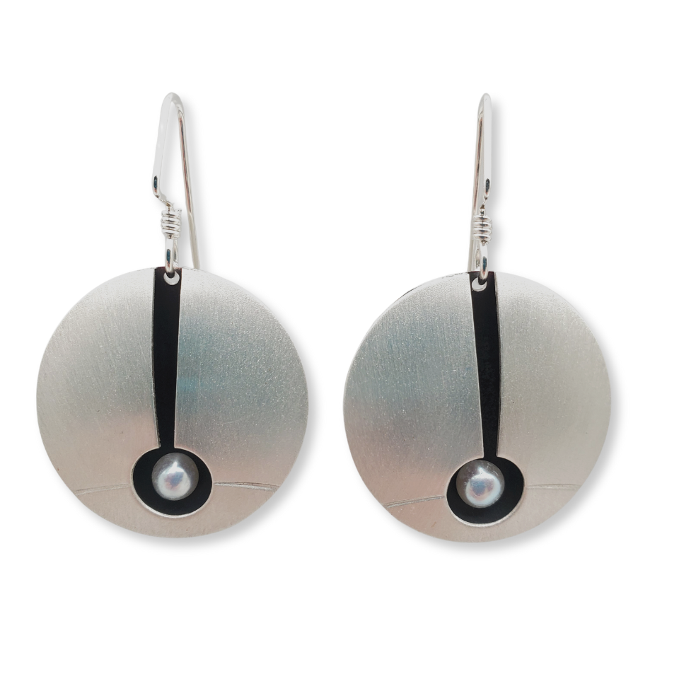 A pair of round silver earrings with a central freshwater pearl detail, suspended from small silver hooks.
