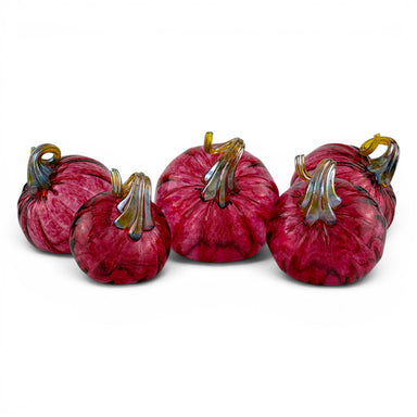 Five decorative glass pumpkins in shades of deep magenta and burgundy, featuring textured marbled patterns and metallic gold and green stems, arranged on a white background.