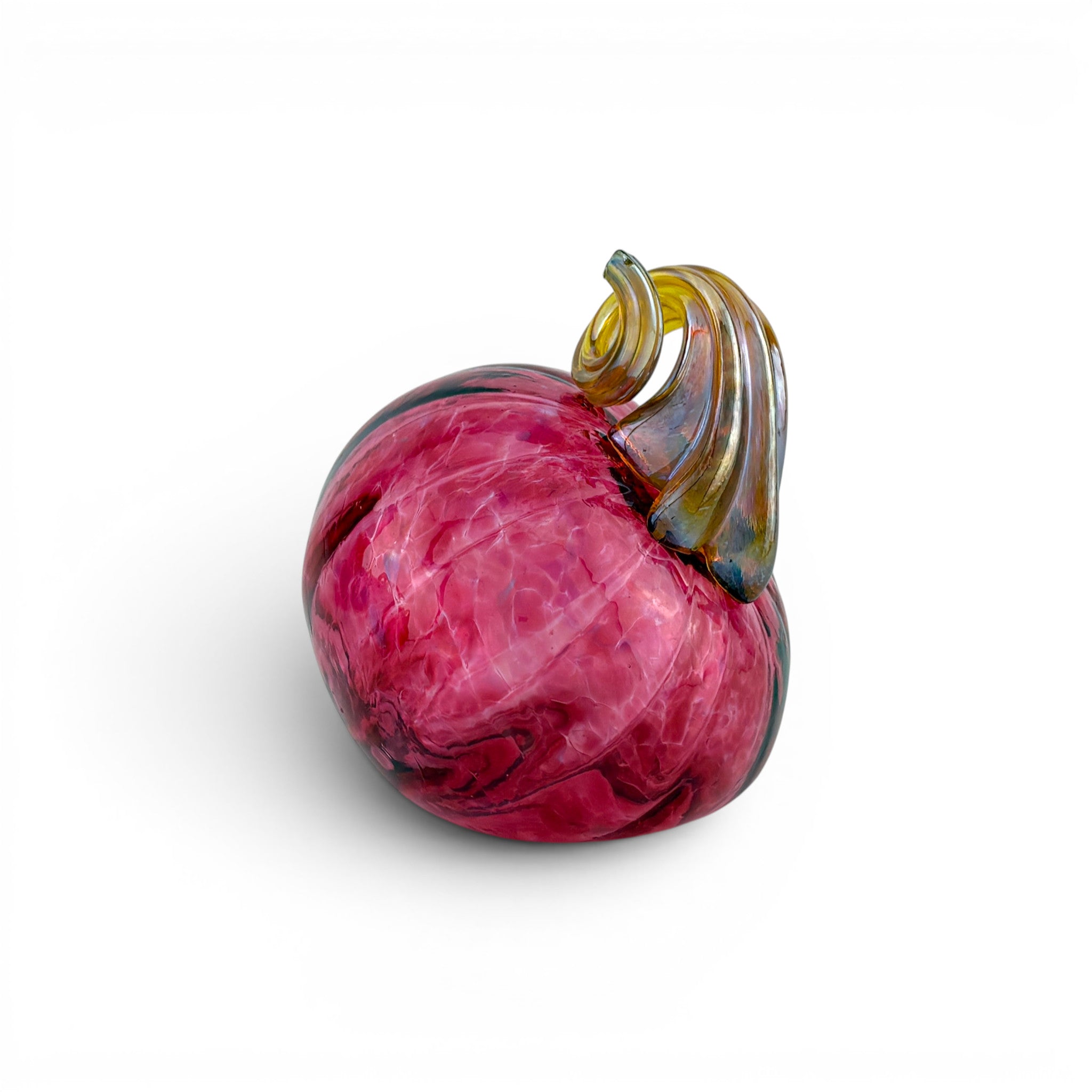 A hand-blown glass decorative object shaped like a stylized fruit or bulb, featuring a deep pink body with marbled purple and blue tones, and a curled stem in amber, gold, and green glass, set against a plain white background.