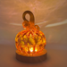A hand-blown glass pumpkin, sitting on an LED display light with a round wooden base, casting a soft glow of yellow, brown, and gold.