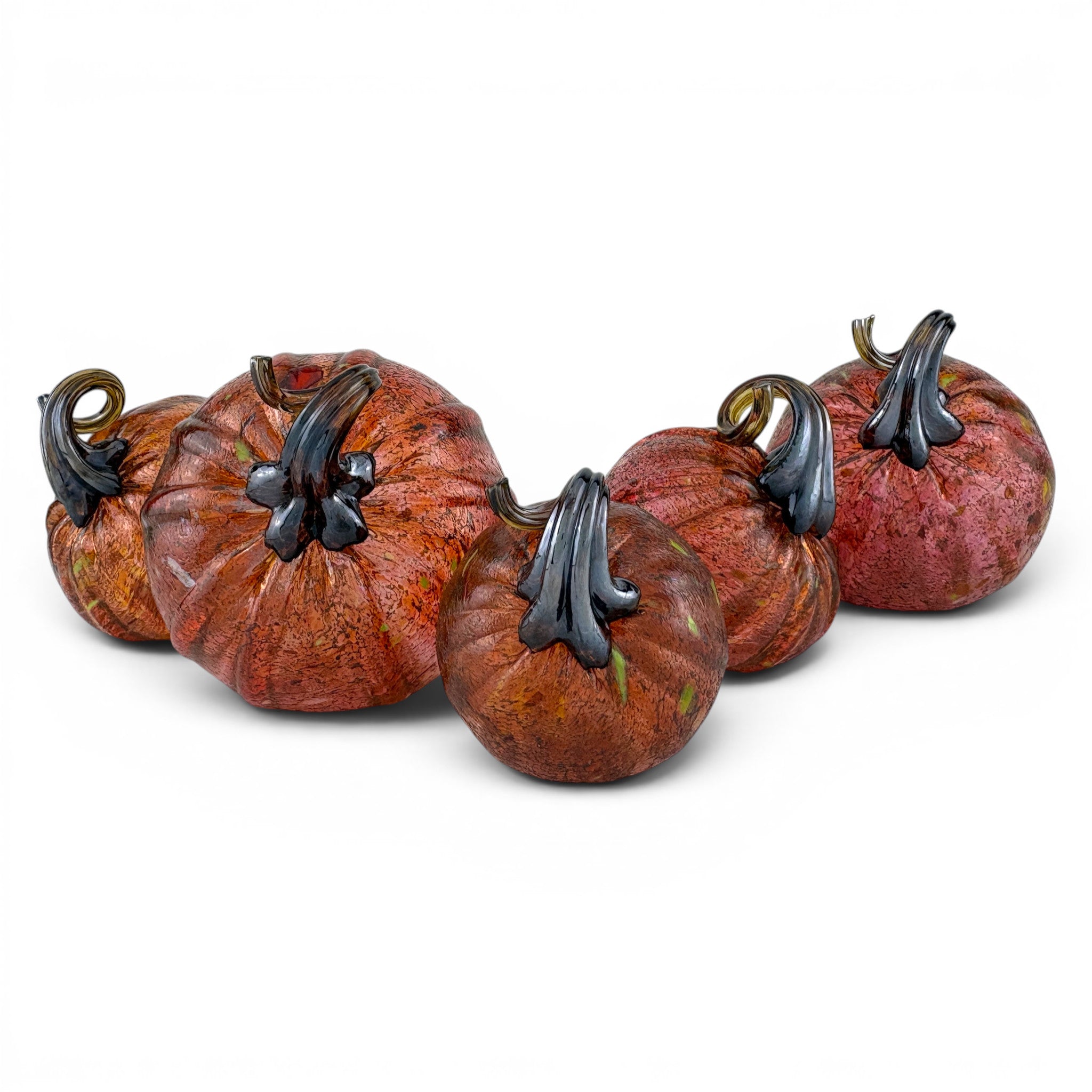 Five decorative glass pumpkins arranged in a row on a white background. The pumpkins have mottled orange, brown, and red tones with dark, sculptural stems.