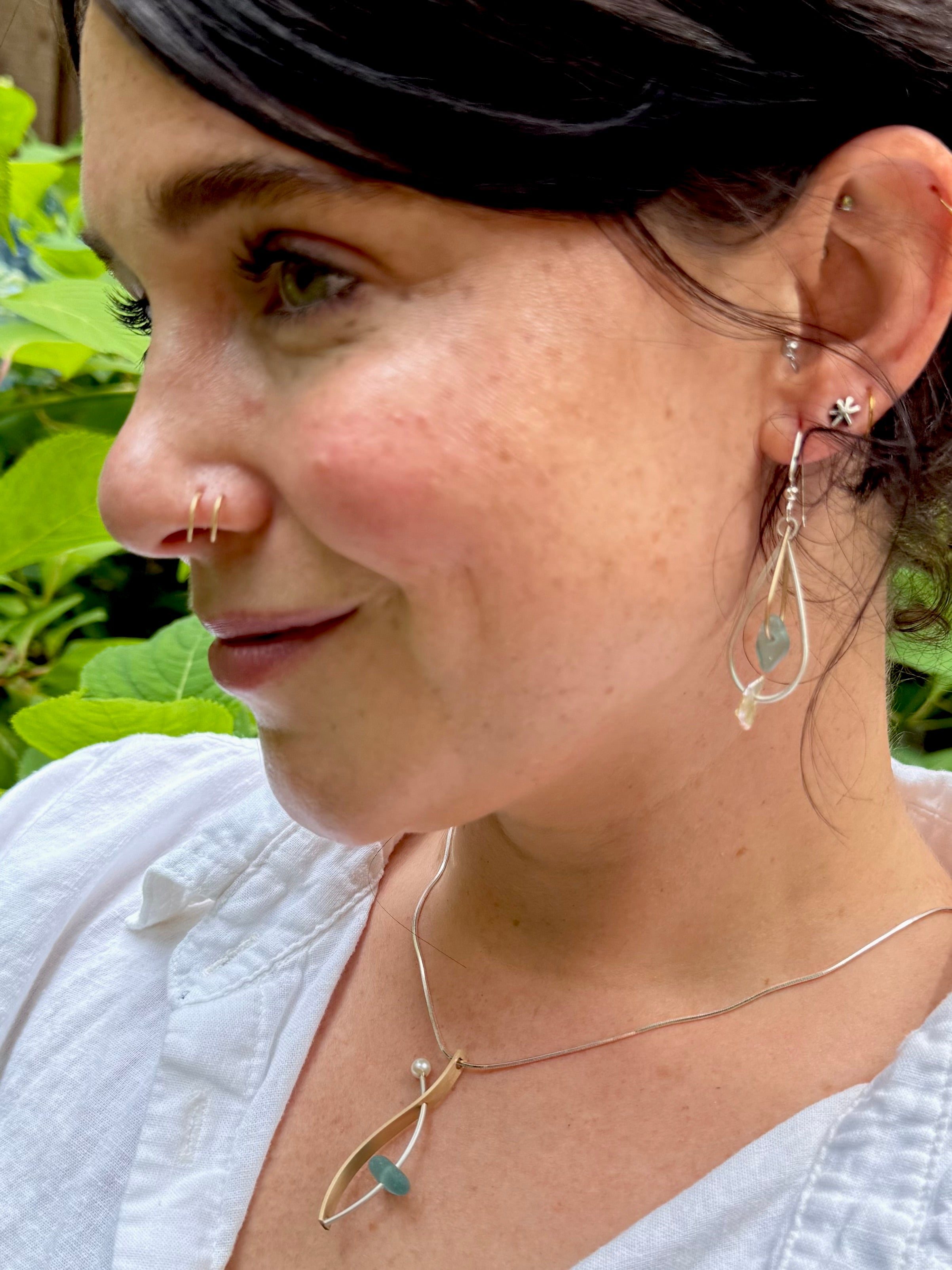 Close-up of a person wearing earrings and a necklace with a natural background