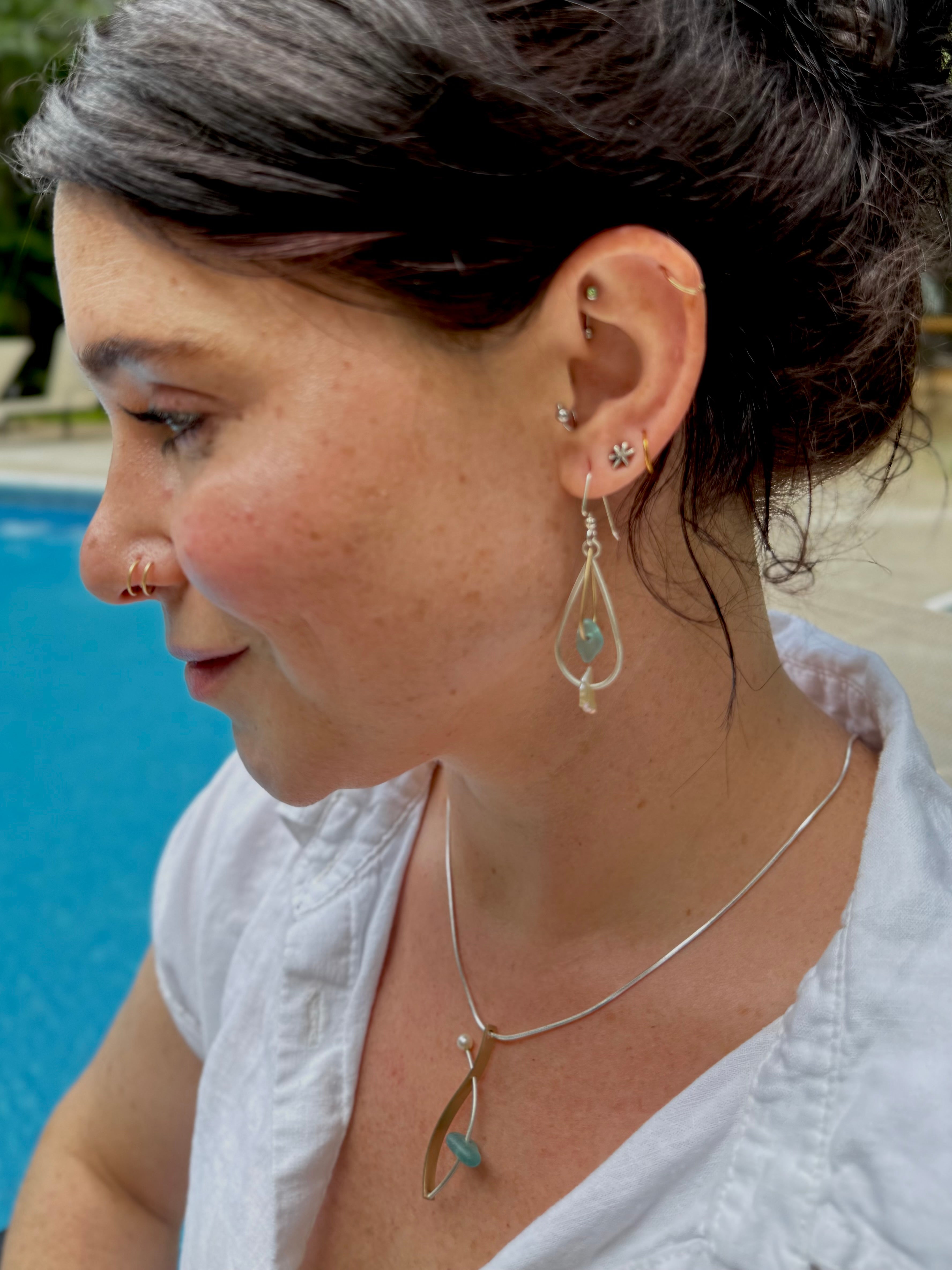 Woman wearing earrings and a necklace with a pool in the background