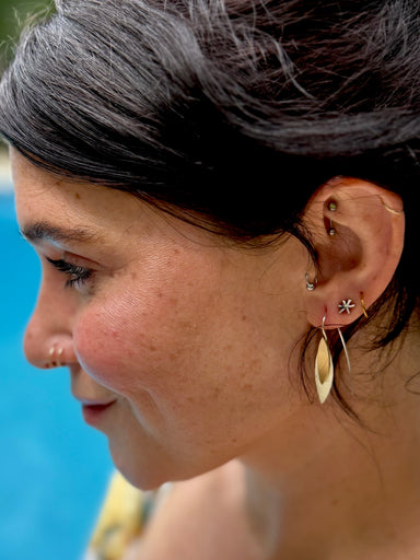Close-up of a person wearing gold earrings with a blurred background