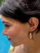 Close-up of a person wearing gold earrings with a blurred background