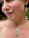 Close-up of a person wearing a silver necklace with a rectangular pendant.