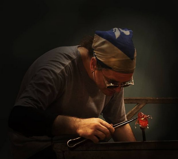 glass artist creating  handcrafted glass penguin