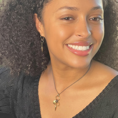 Woman wearing a necklace with a pendant against a neutral background