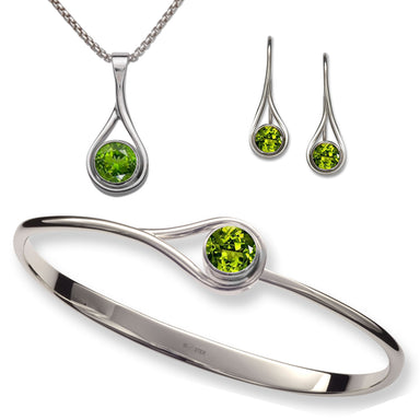 A set of sterling silver jewelry including a bracelet, a pendant, and a pair of earrings, all featuring bezel green peridot stones.