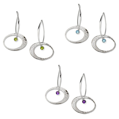 A set of three silver earrings, each with a different colored gemstone accent: blue topaz, amethyst, and peridot.