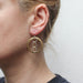 handcrafted silver and brass earrings on a model