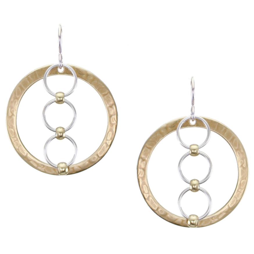 A pair of earrings featuring a wide brass ring with three smaller silver rings suspended in the center, hanging from silver ear wires.