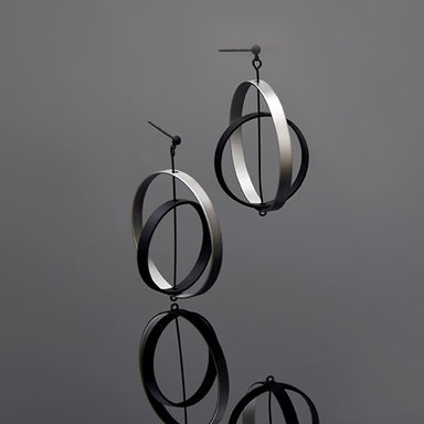 A pair of silver axle earrings with a matte finish, displayed against a gray background.