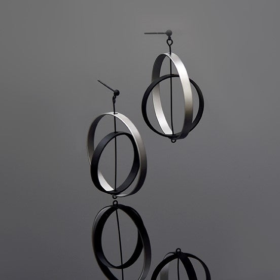 A pair of silver axle earrings with a matte finish, displayed against a gray background.